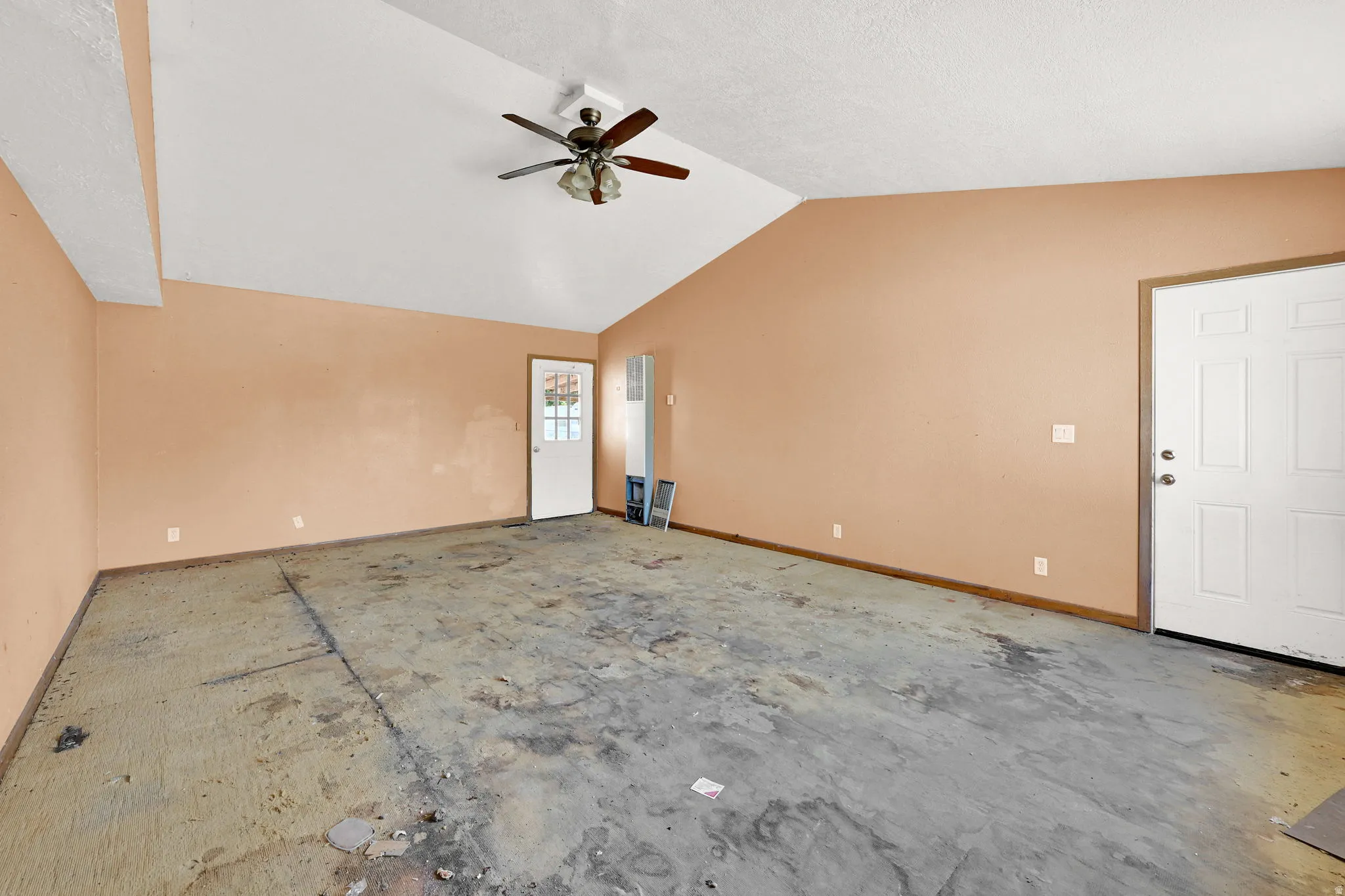 Spacious room featuring a vaulted ceiling with a ceiling fan