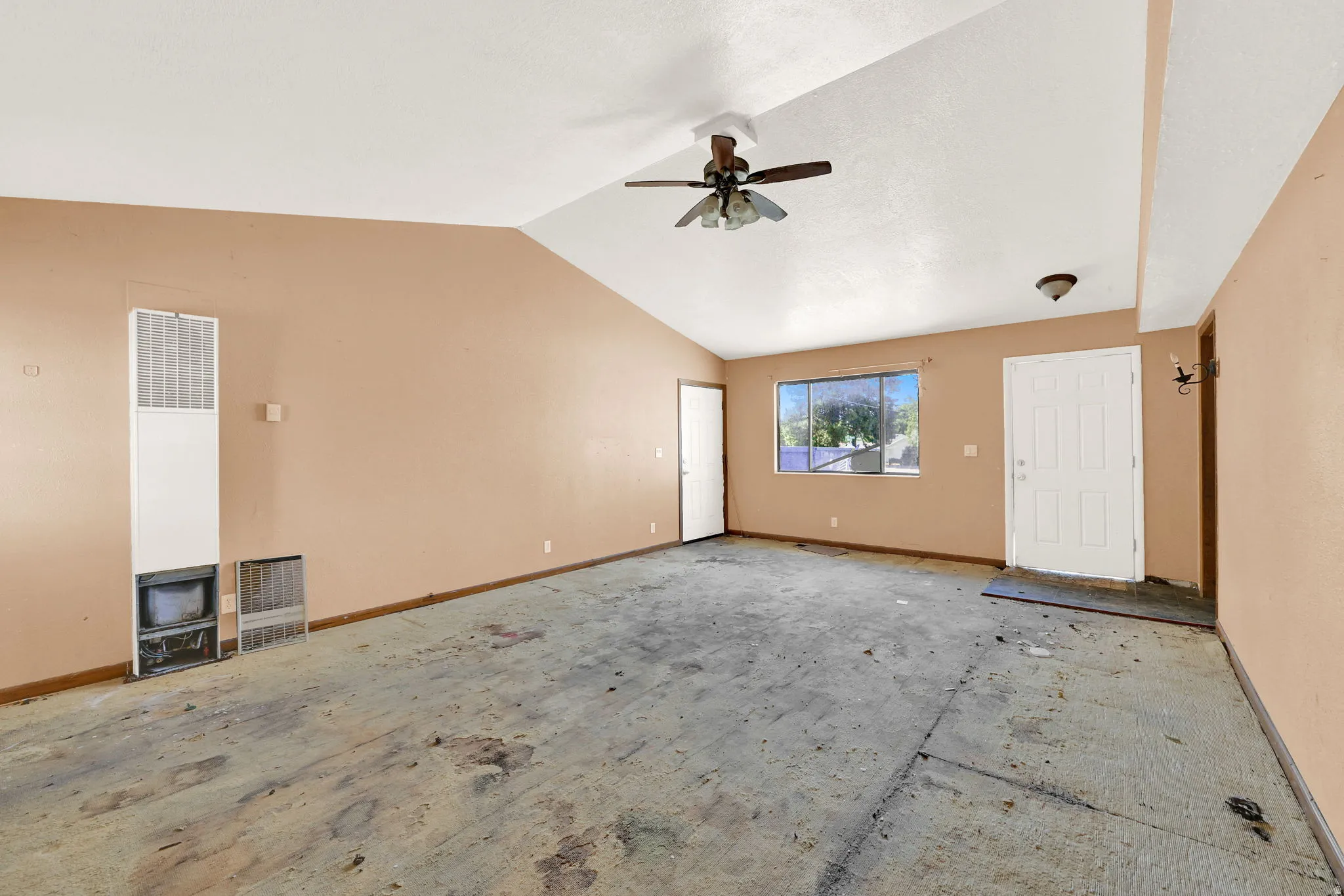 Spacious room with vaulted ceilings, a ceiling fan, and a large window