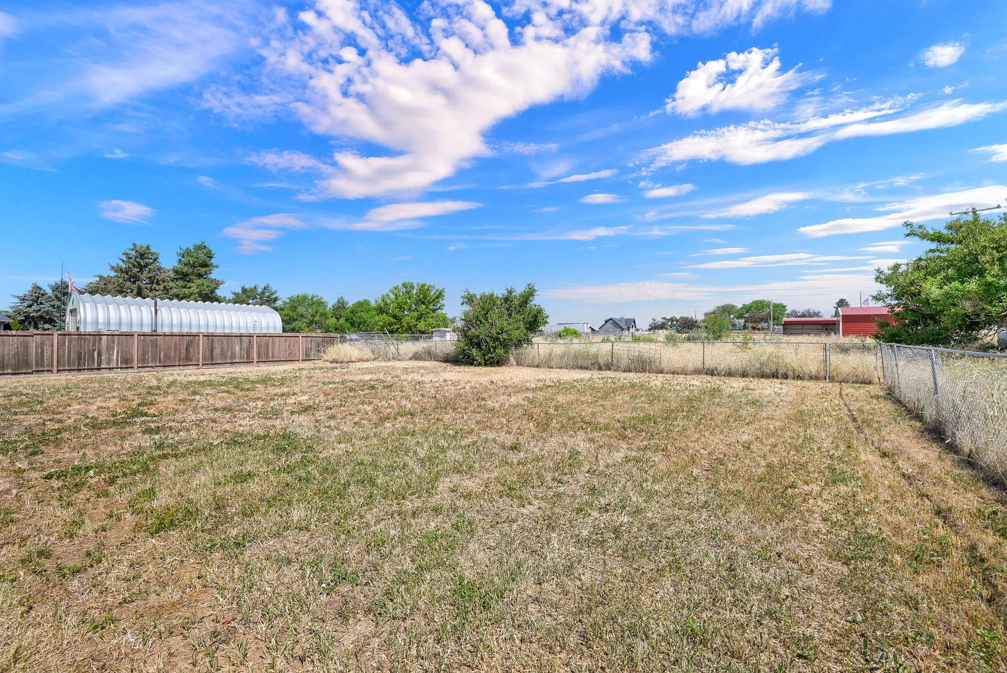 Expansive outdoor space featuring a partial wood privacy fence and a chain link fence
