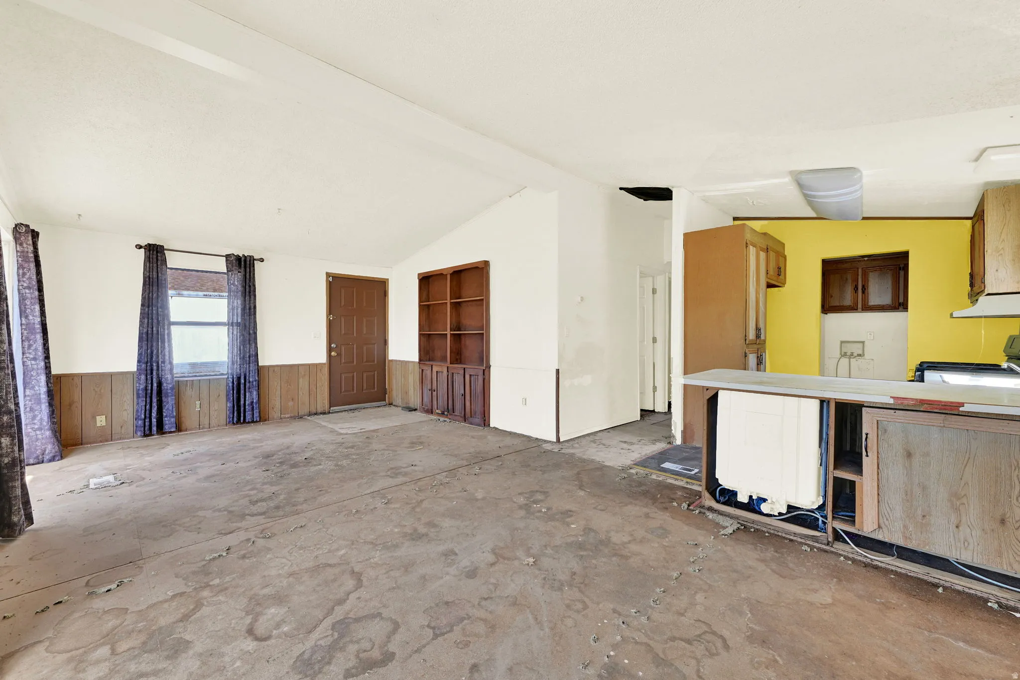 Living area with vaulted ceiling, paneled wainscoting, and built-in shelving