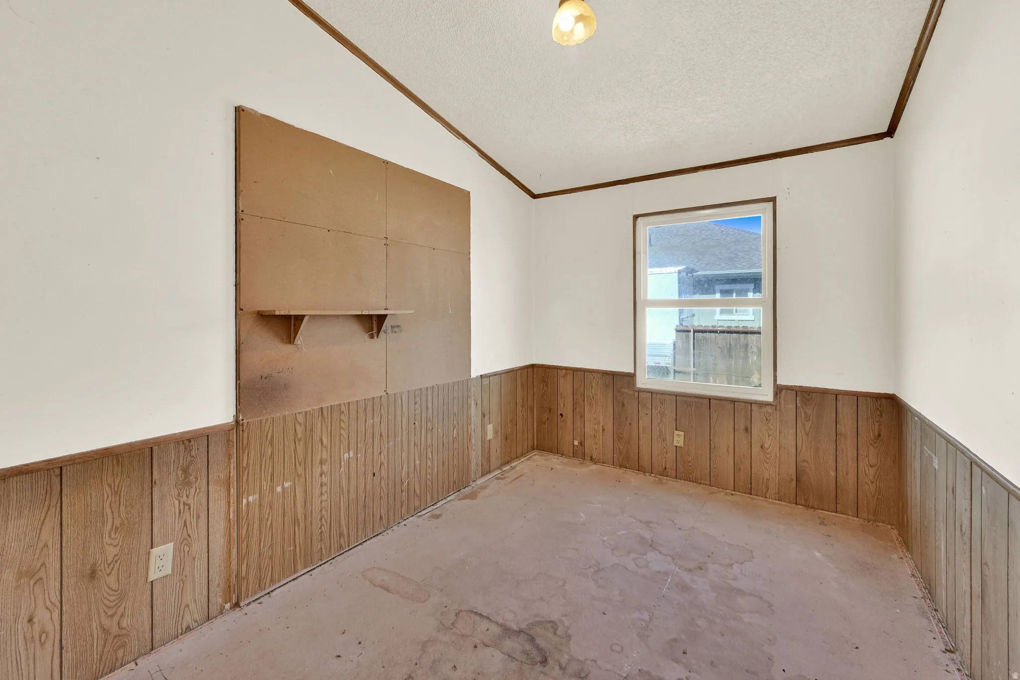 Room featuring a single-pane window, wood-finish paneling, and a flush-mount ceiling light fixture