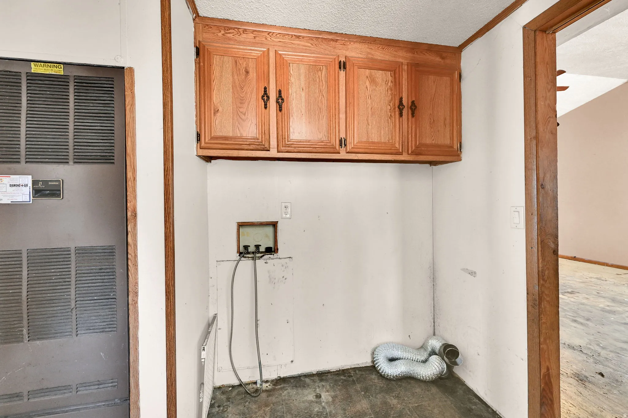 Laundry area featuring overhead wood cabinetry and utility hookups