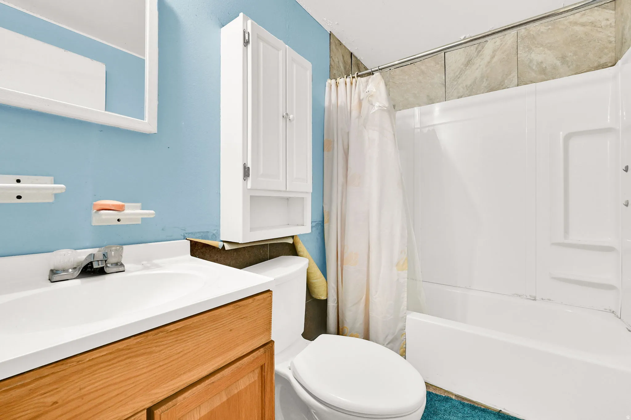 Bathroom featuring a white vanity with wood-finish cabinetry, a white basin, and a chrome faucet