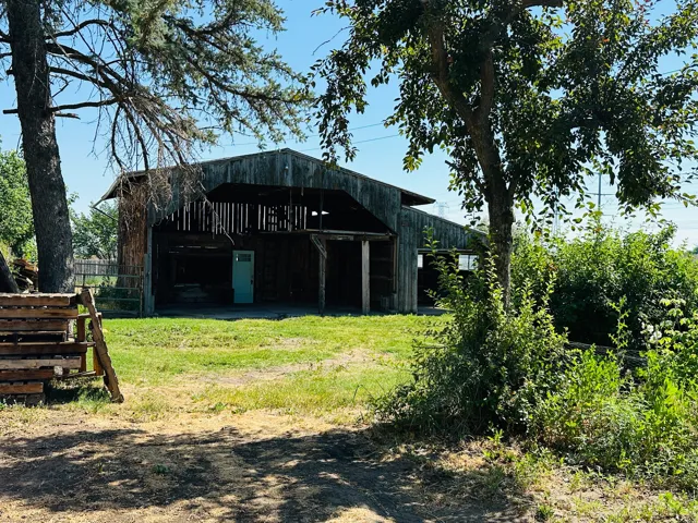 Rustic wood barn structure featuring a gabled roof and a light blue entry door