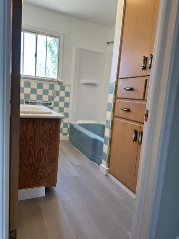 Light wood-finish flooring with a wood-finish vanity and built-in cabinetry