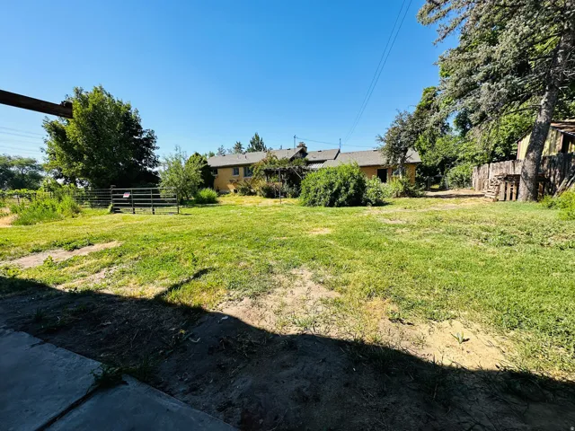 Expansive grassy area featuring mature trees and a wooden fence