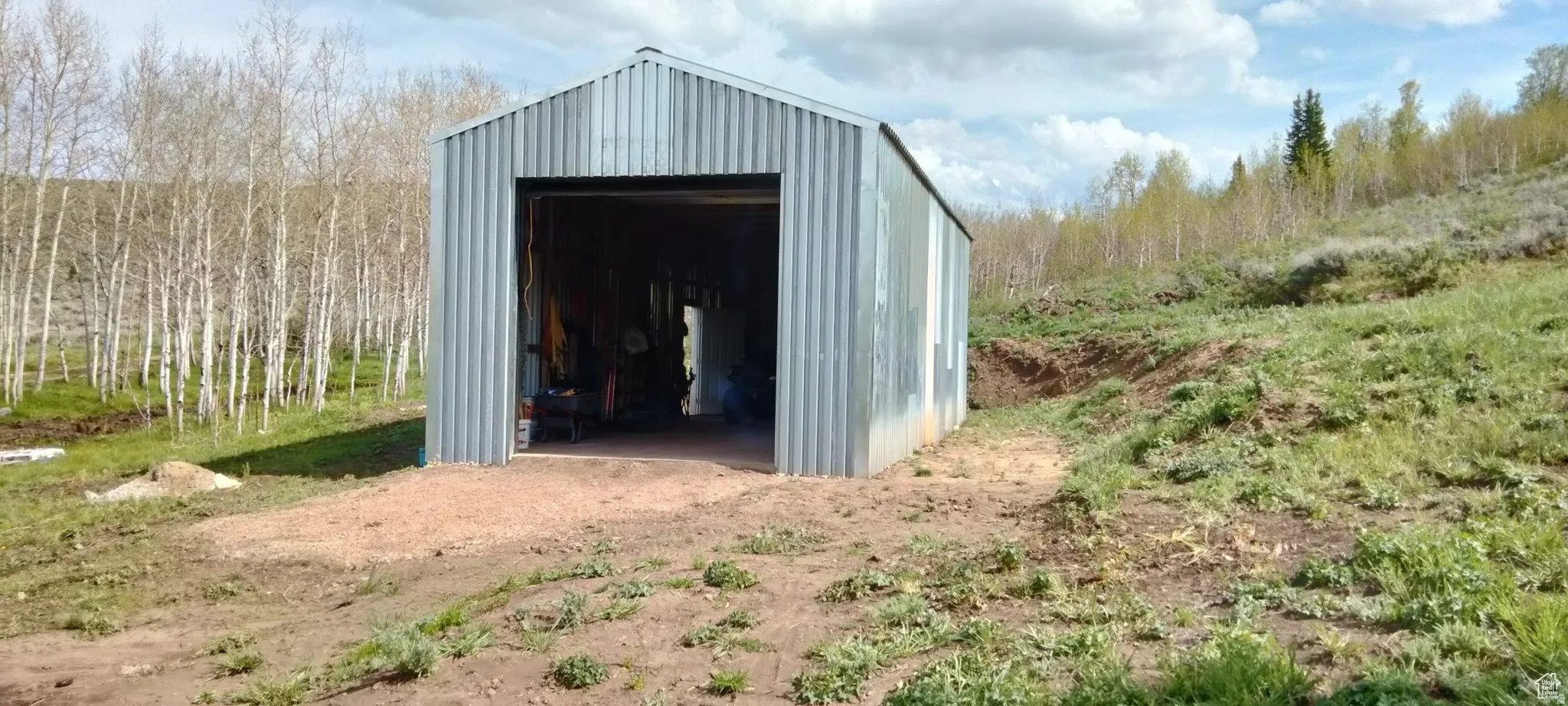 Corrugated metal outbuilding featuring a wide entry door