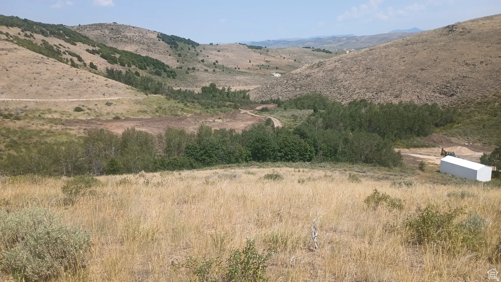 Expansive natural landscape featuring rolling hills, varied topography, and a mix of arid and green vegetation