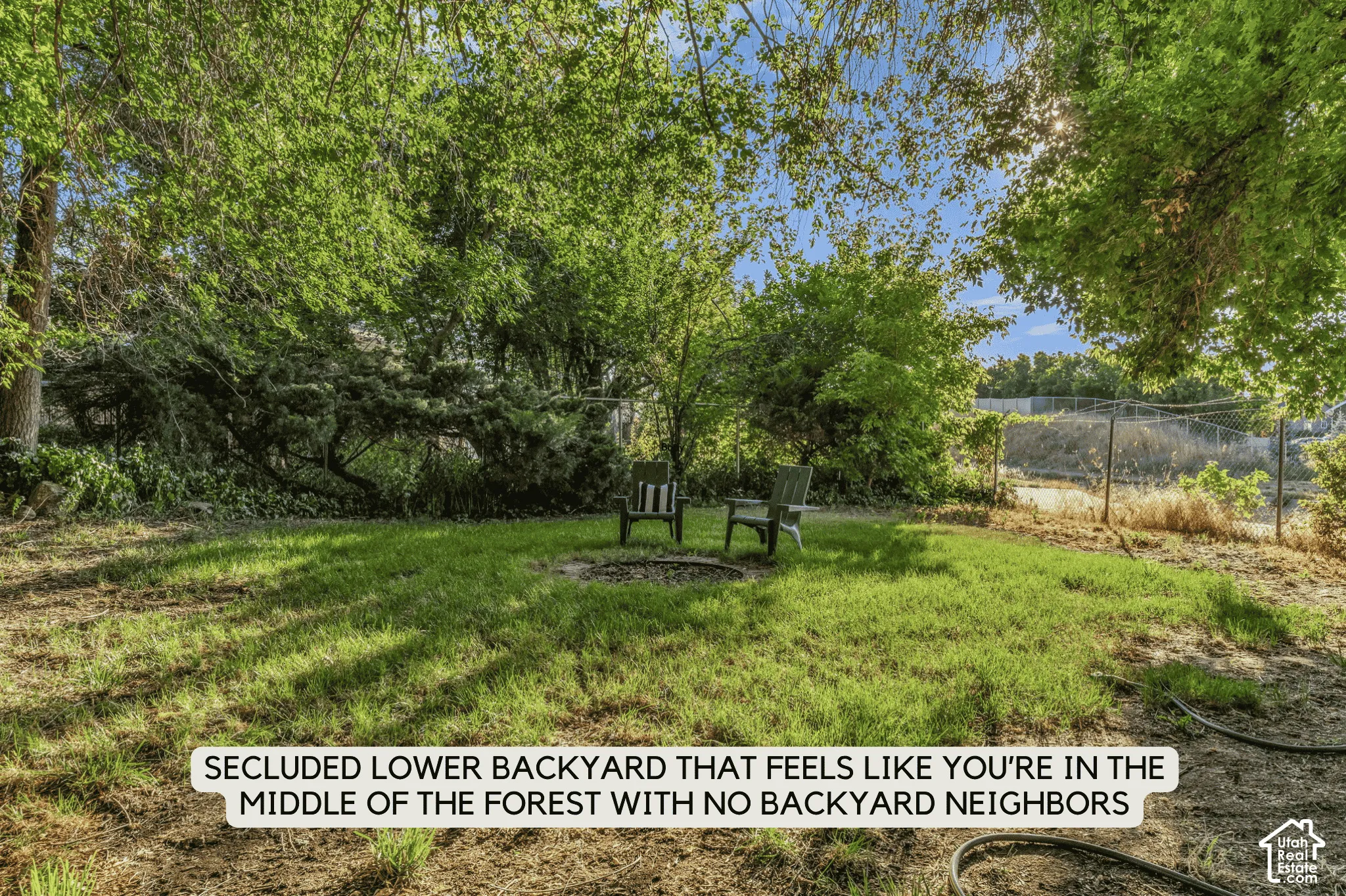 Expansive backyard with a central fire pit, surrounded by mature trees and lush green foliage