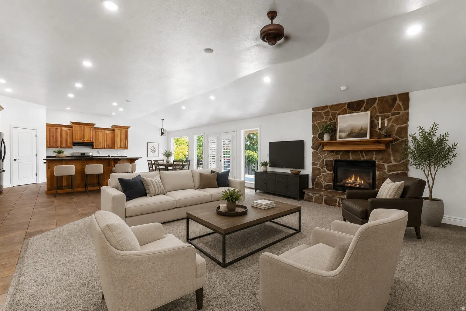 Spacious open-concept living area featuring a stone fireplace, wood mantel, and vaulted ceilings with recessed lighting