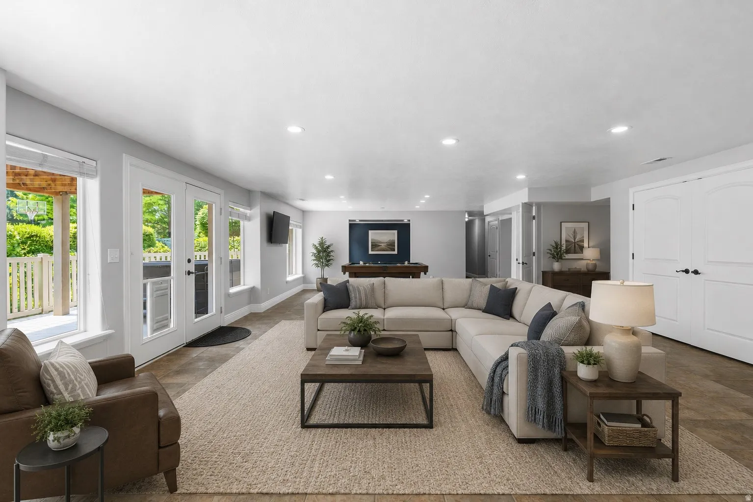 Spacious living area featuring light-toned walls, recessed lighting, and wood-finish flooring