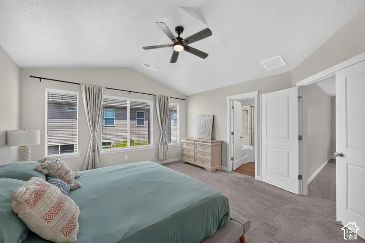 Spacious bedroom featuring vaulted ceilings, a ceiling fan with integrated lighting, and multiple windows with blinds