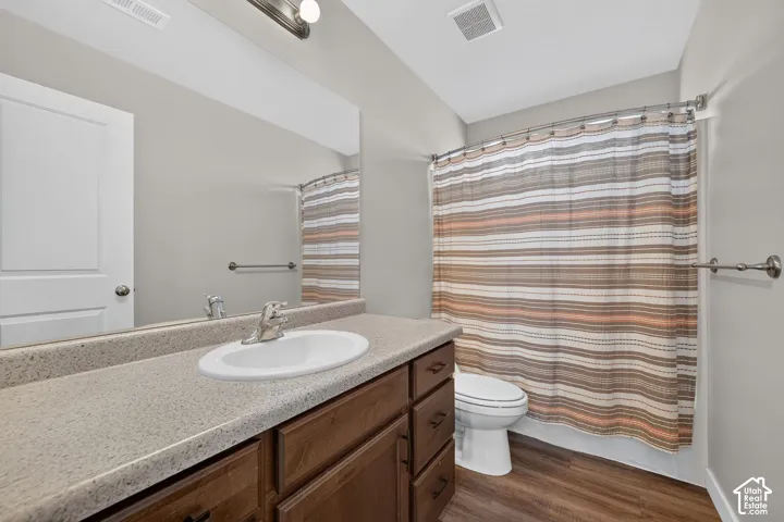 Bathroom featuring a single vanity with an integrated sink, a speckled countertop, and wood-finish cabinetry