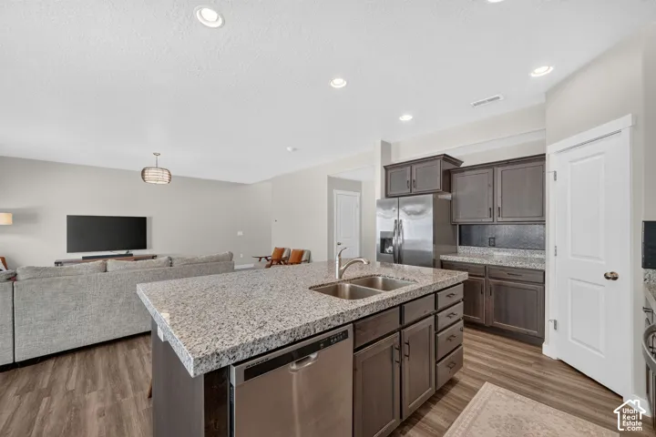 Kitchen island featuring a double-basin sink, stainless steel dishwasher, and a light-toned countertop