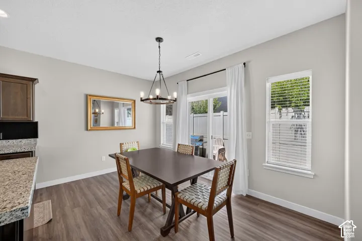 Dining area featuring wood-finish flooring, a contemporary chandelier, and light gray wall paint