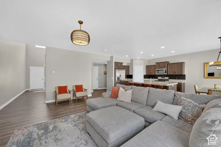 Open-concept living space featuring wood-finish flooring, recessed lighting, and a kitchen with dark cabinetry and a light-toned countertop