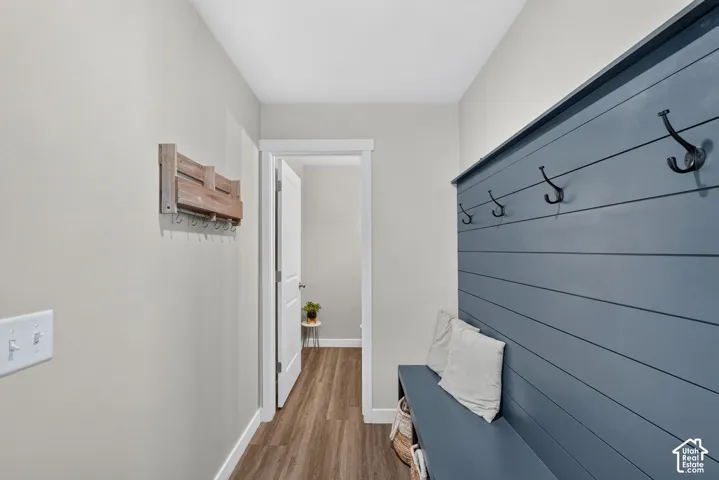 Entryway featuring a built-in bench with storage, shiplap wall accent, and five black coat hooks