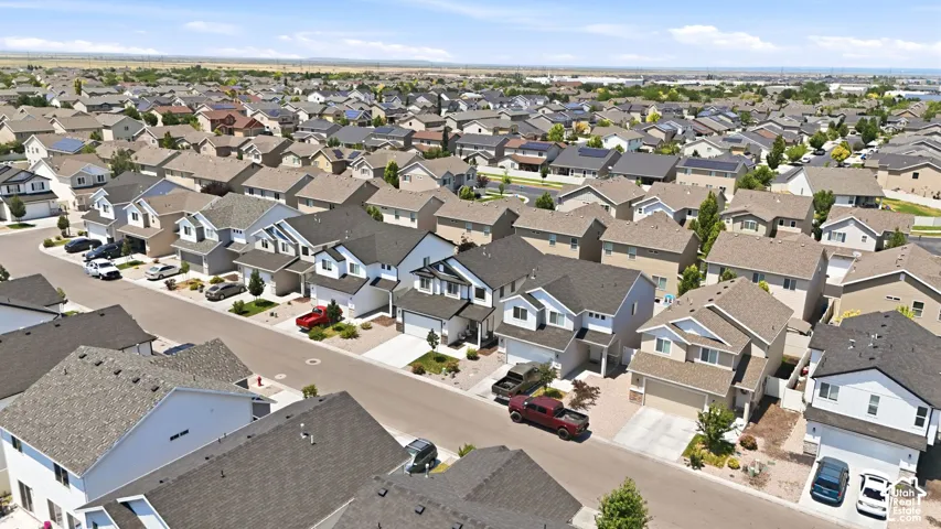 Residential street featuring multiple two-story homes with attached garages, shingle roofs, and light-toned siding