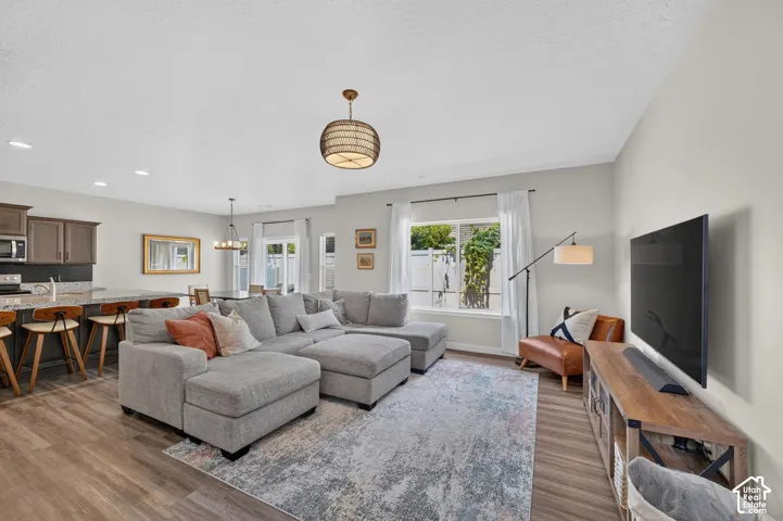 Open-concept living area featuring wood-finish flooring, recessed lighting, and a kitchen island with stone countertops