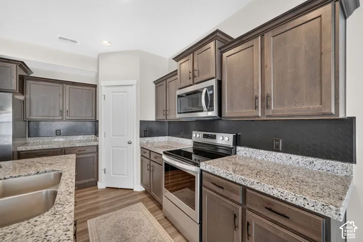Kitchen featuring wood-finish cabinetry, light-toned countertops, and a black honeycomb-patterned backsplash