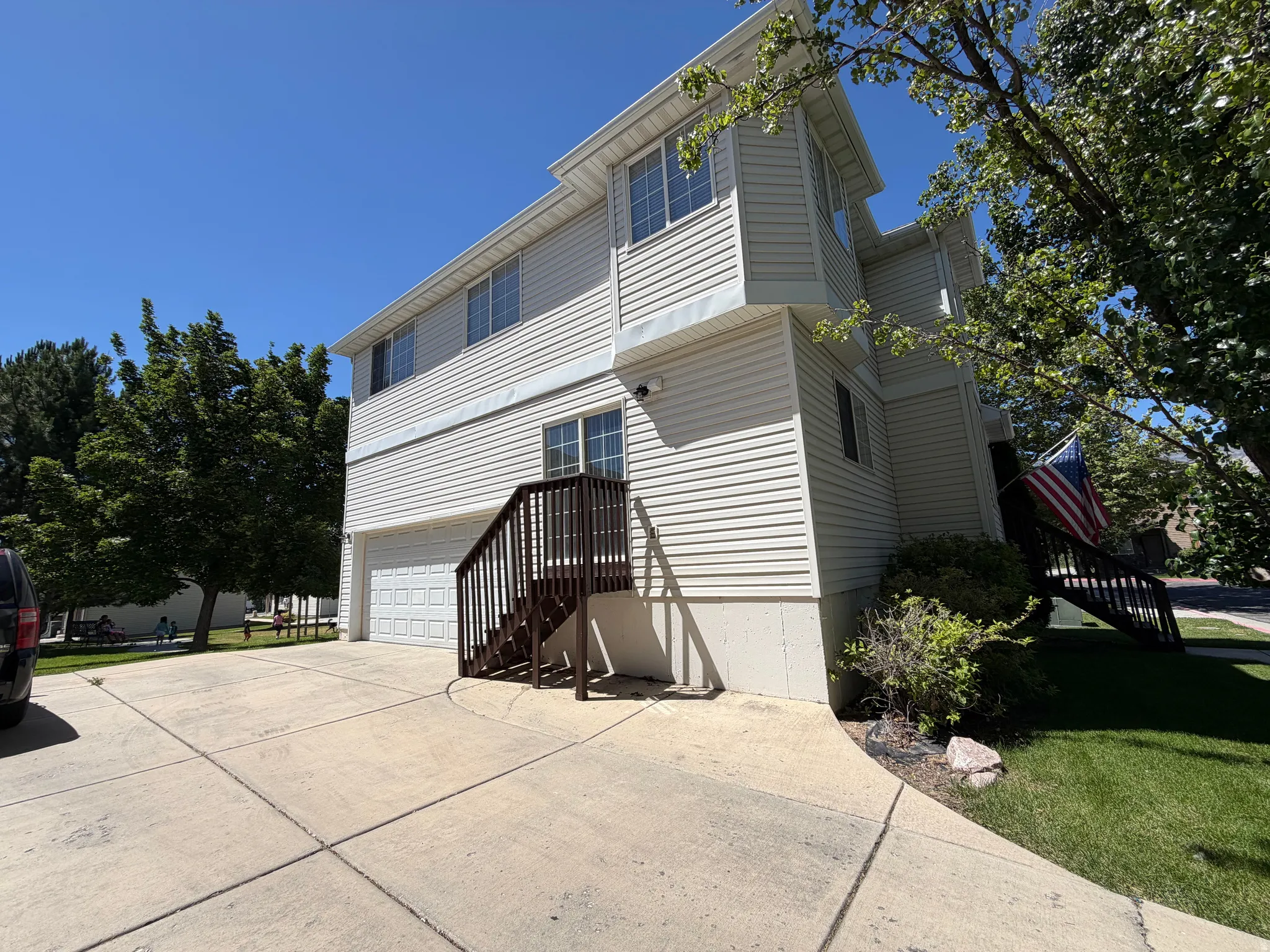 Two-story residence featuring light-colored siding, multiple windows, and a two-car garage