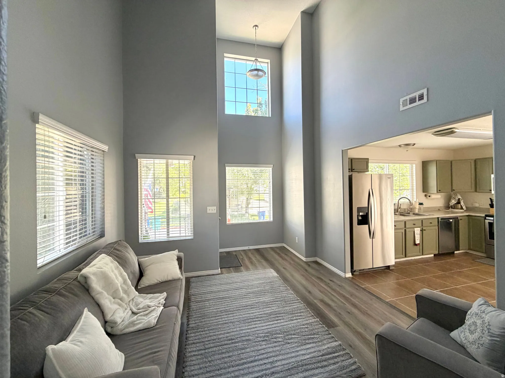 Living area featuring vaulted ceilings, wood-finish flooring, and multiple windows