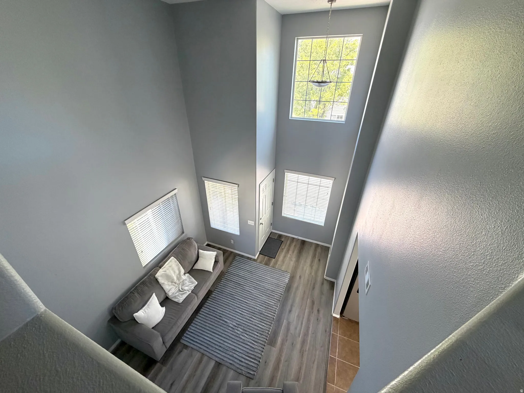 Two-story entryway with vaulted ceilings, large picture windows, wood-finish flooring, and a decorative chandelier