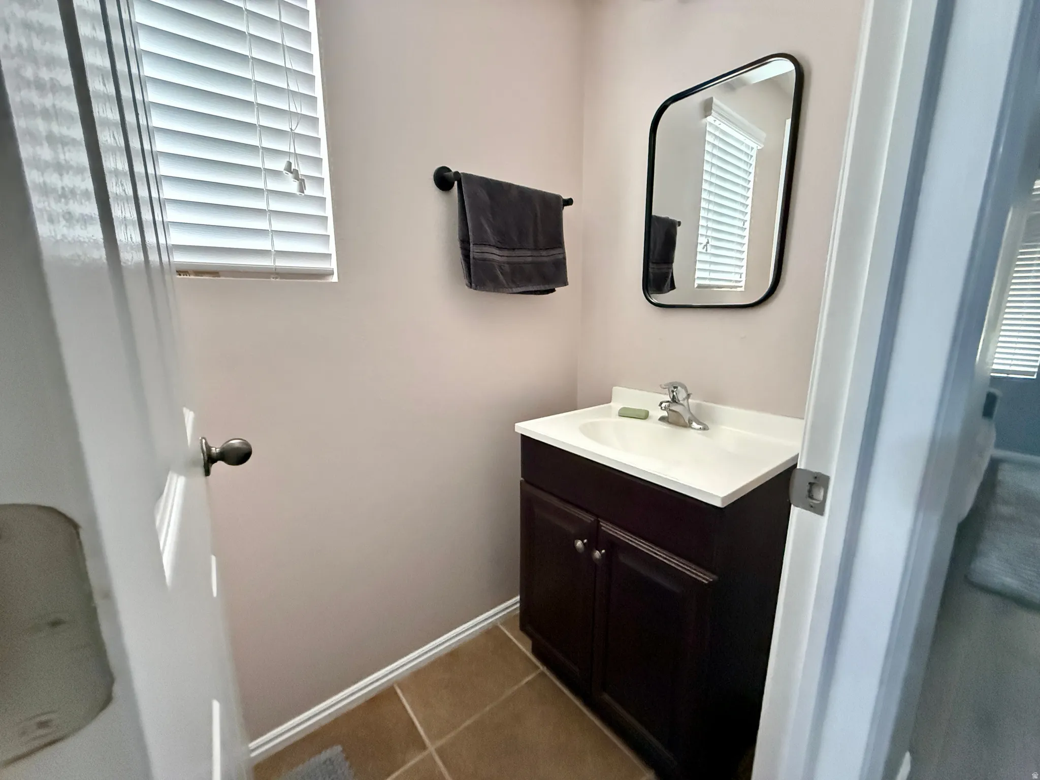Bathroom vanity featuring a dark wood-finish cabinet with a white countertop and integrated sink