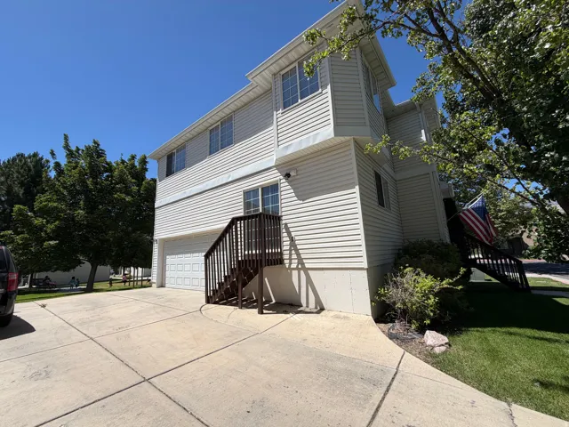 Two-story residence featuring light-colored siding, multiple windows, and a two-car garage