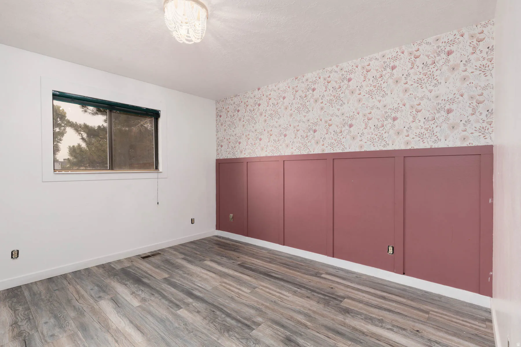Interior room featuring wood-finish flooring, a window, and a decorative wall with wainscoting and floral wallpaper