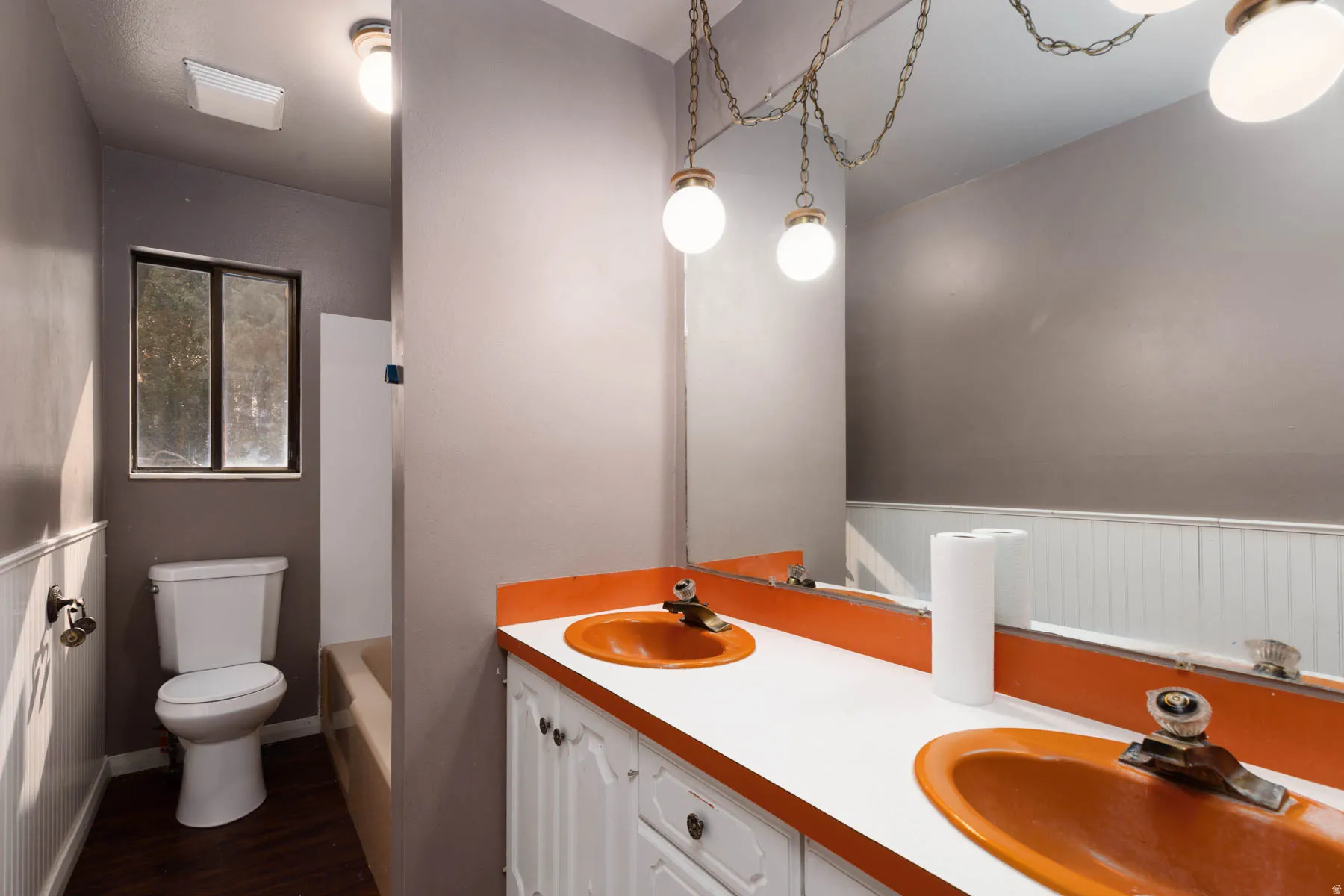 Bathroom vanity featuring dual orange sinks and white cabinetry, complemented by a large wall-mounted mirror
