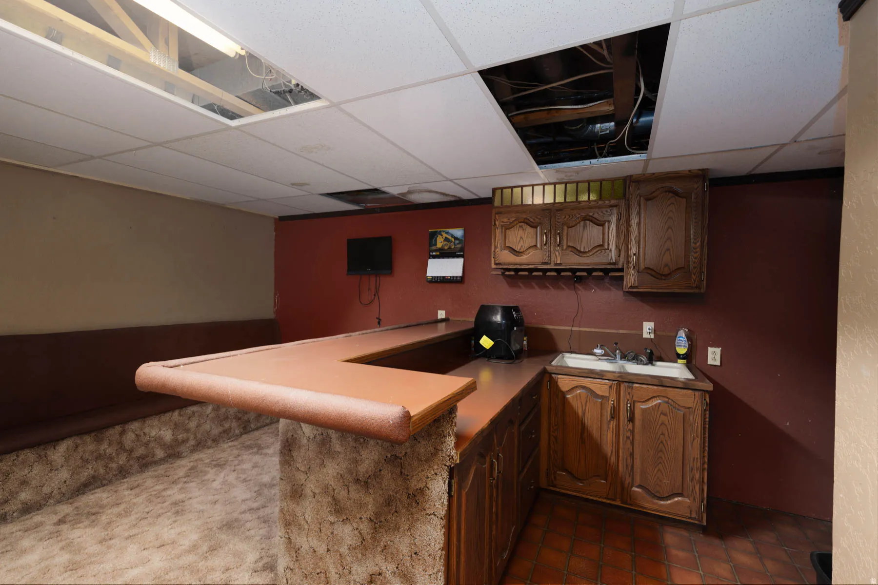 Wet bar featuring wood-finish cabinetry, a built-in sink, and tile flooring