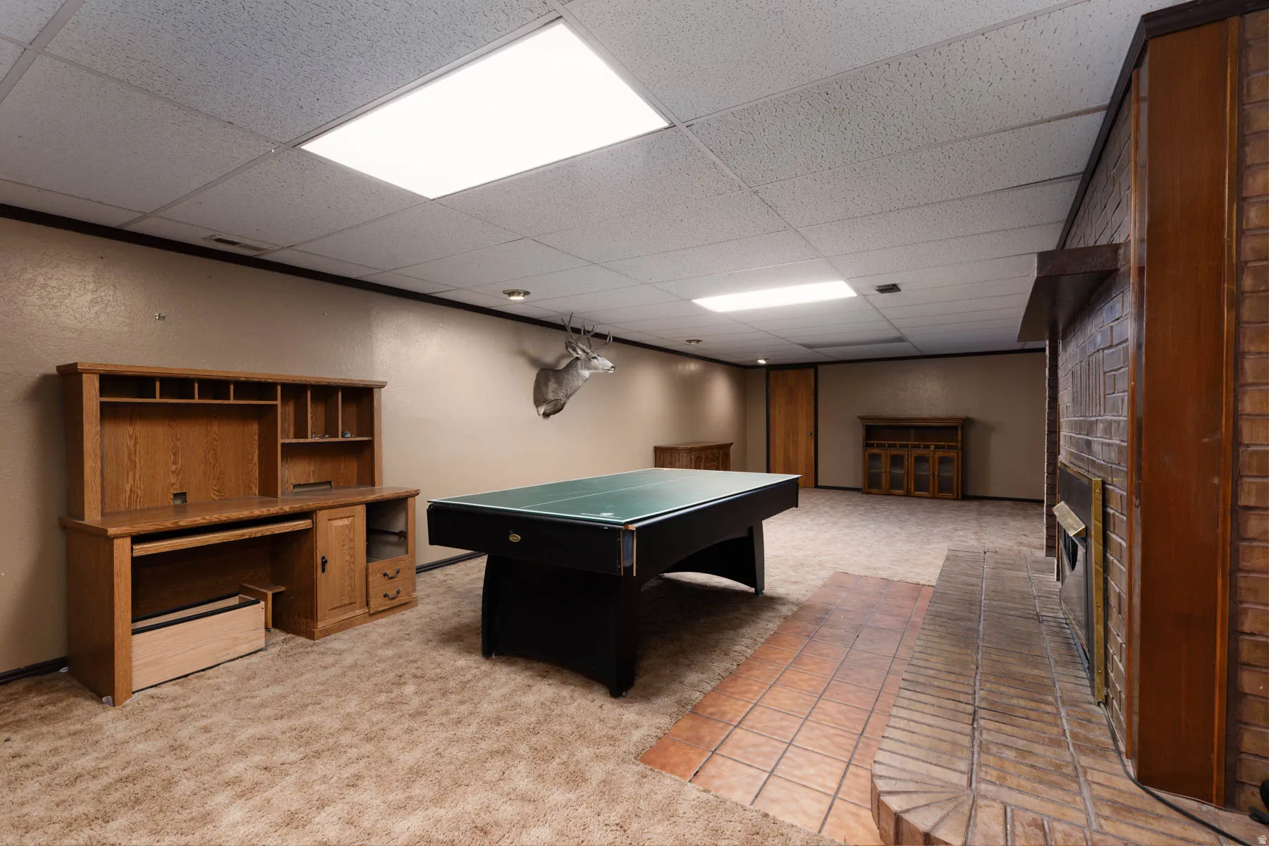 Spacious room featuring a brick fireplace with a raised hearth, light tan walls, and recessed ceiling lighting