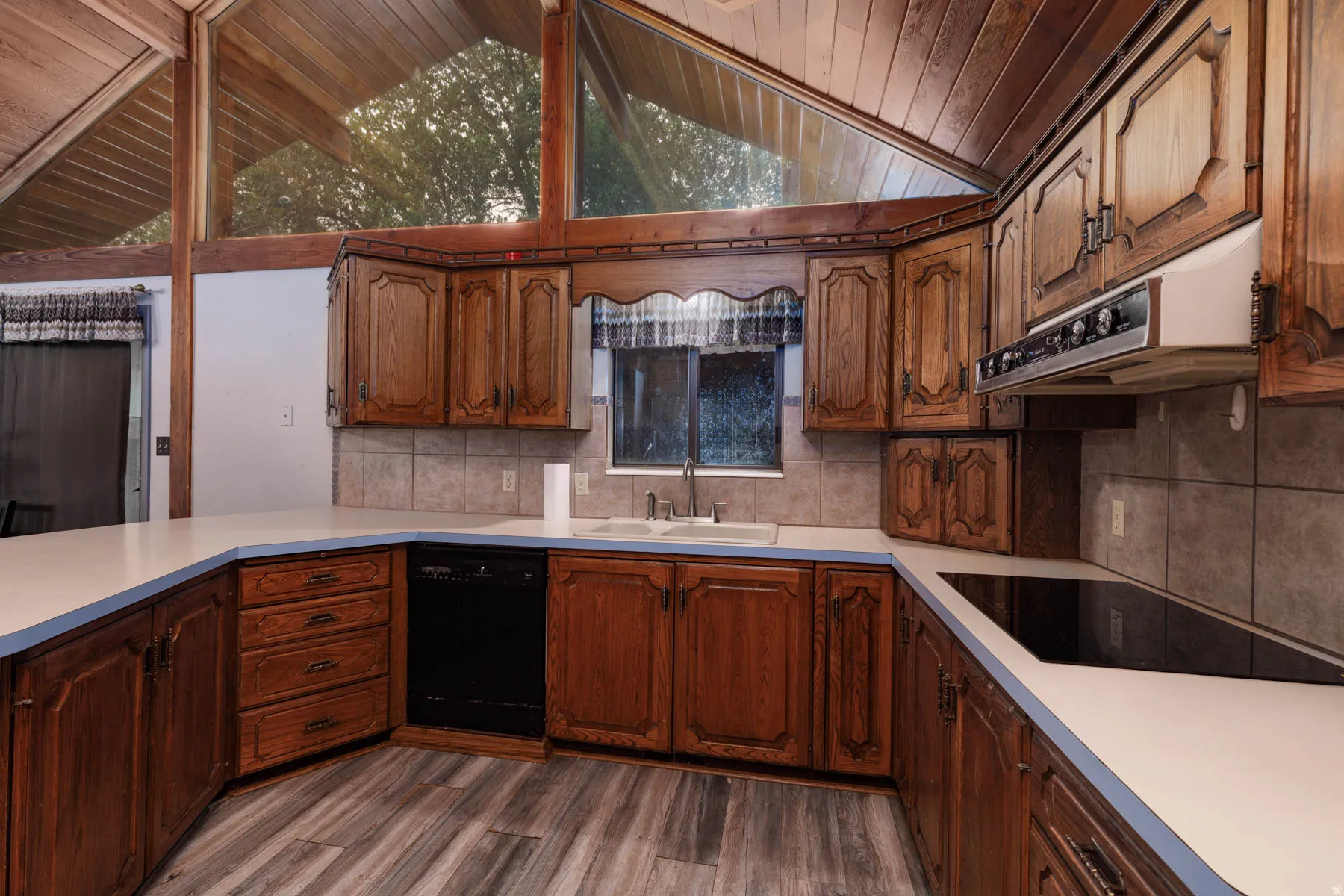 Kitchen featuring wood-finish cabinetry, light countertops with blue trim, and a built-in cooktop
