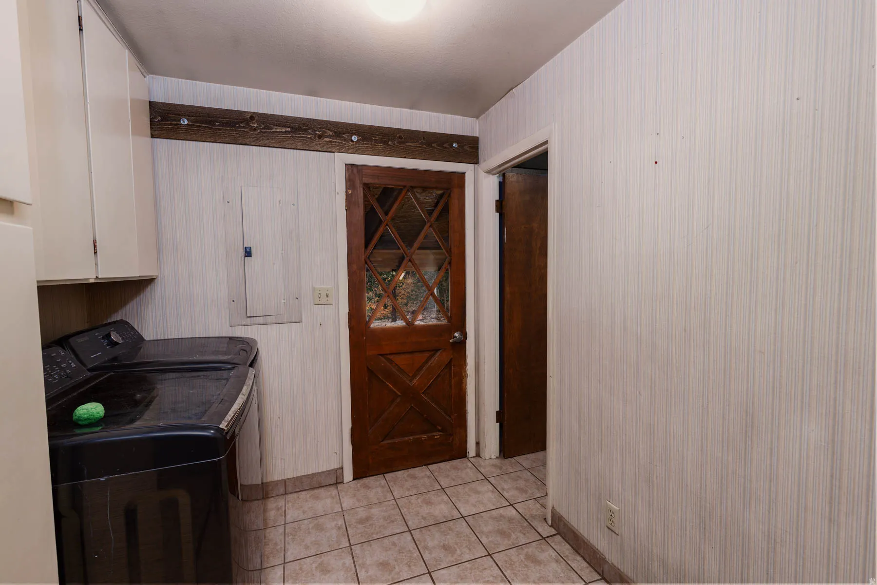 Utility area with light-toned wall paneling and neutral tile flooring