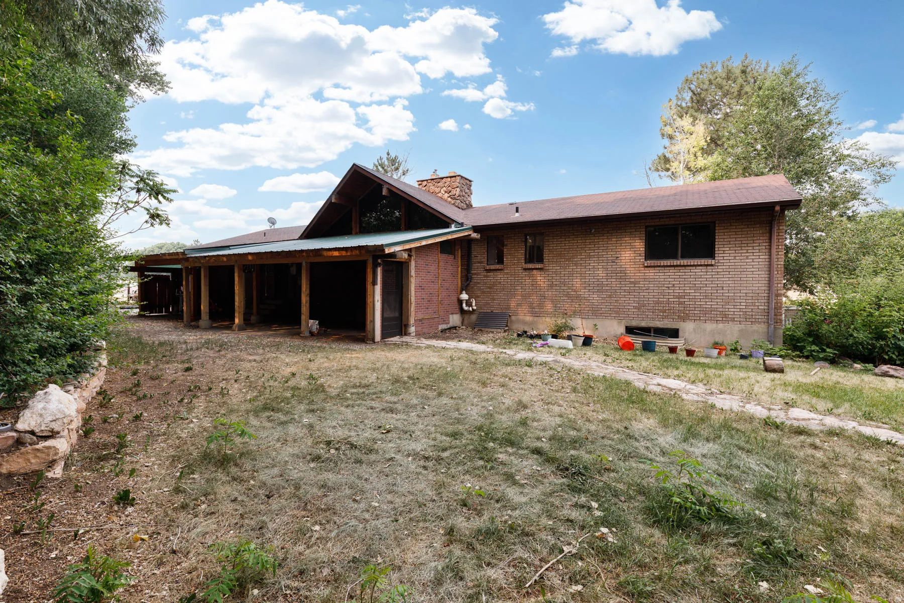 Brick exterior with a brown shingle roof and a covered patio featuring wood support columns
