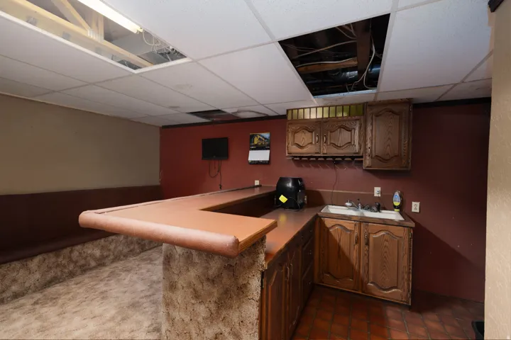 Wet bar featuring wood-finish cabinetry, a built-in sink, and tile flooring