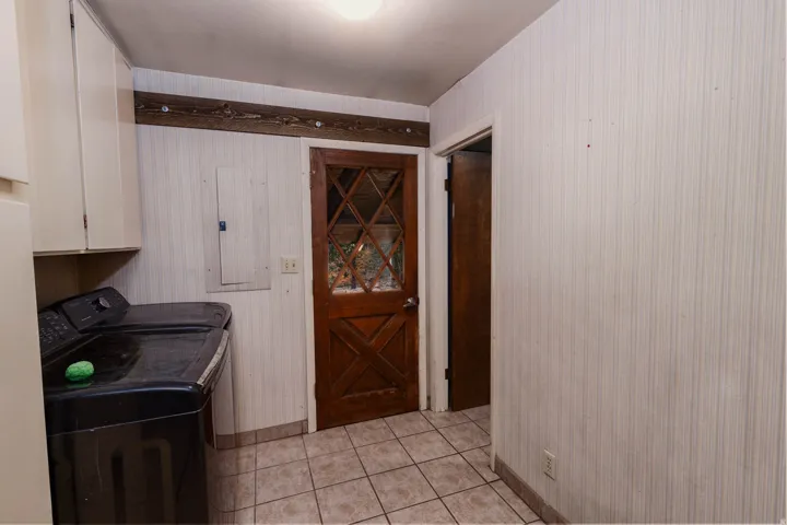 Utility area with light-toned wall paneling and neutral tile flooring
