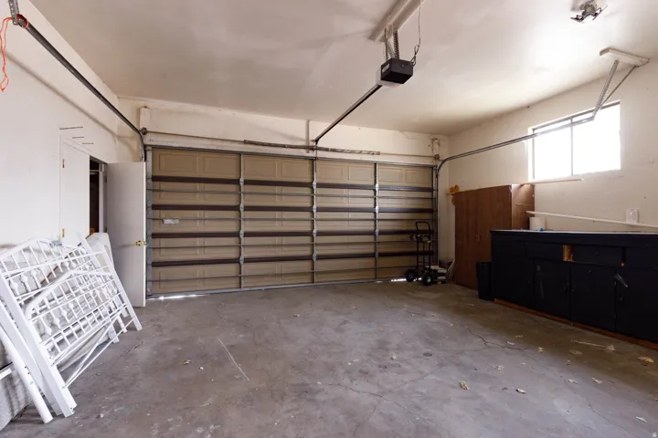 Spacious garage featuring a roll-up door, automatic opener, a built-in window, and an interior access door