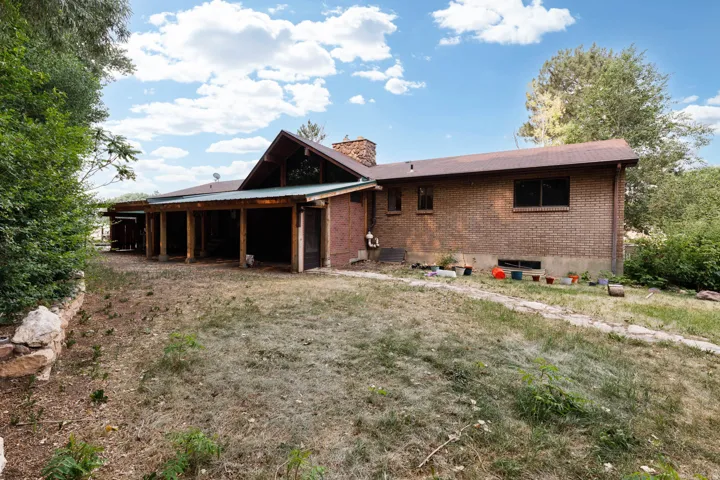 Brick exterior with a brown shingle roof and a covered patio featuring wood support columns