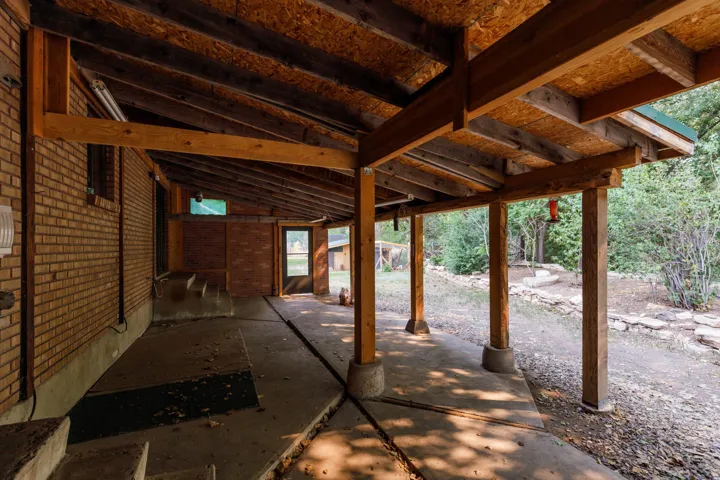 Covered patio featuring a concrete floor, exposed wood beam ceiling, and brick exterior wall