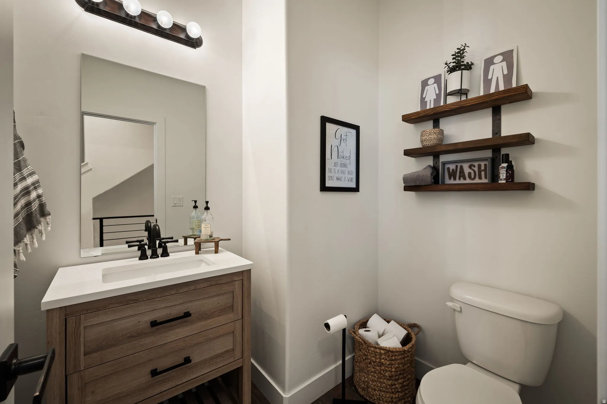 Modern vanity featuring wood-finish cabinetry, a white countertop, and a rectangular undermount sink with a matte black faucet