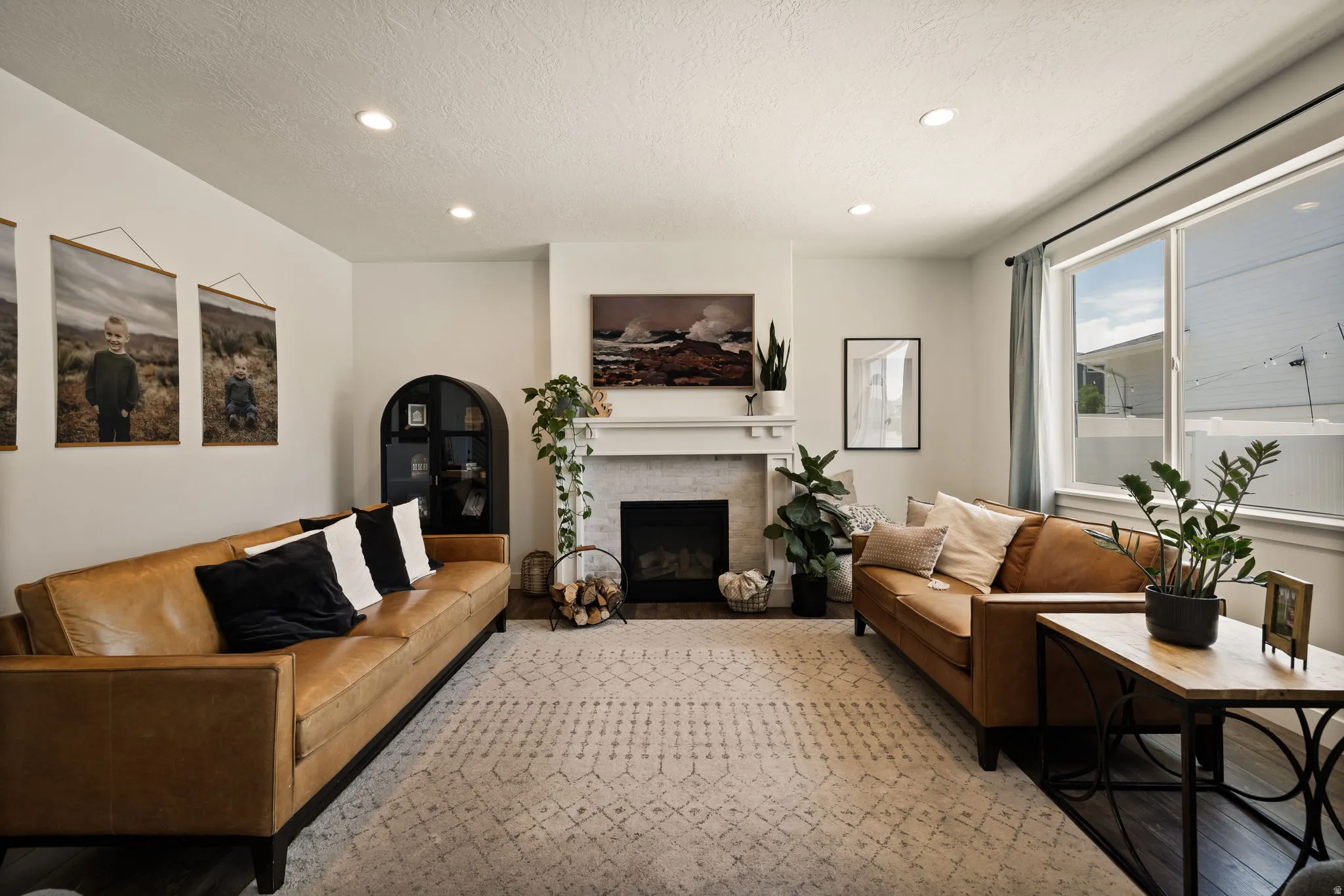 Bright living area featuring a fireplace with a white mantel and stone-finish surround, recessed lighting, expansive windows, and dark wood-finish flooring