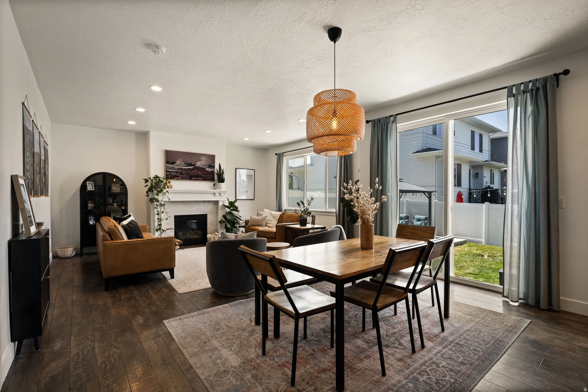 Open-concept living and dining area featuring wood-finish flooring, recessed lighting, and a fireplace with a mantel