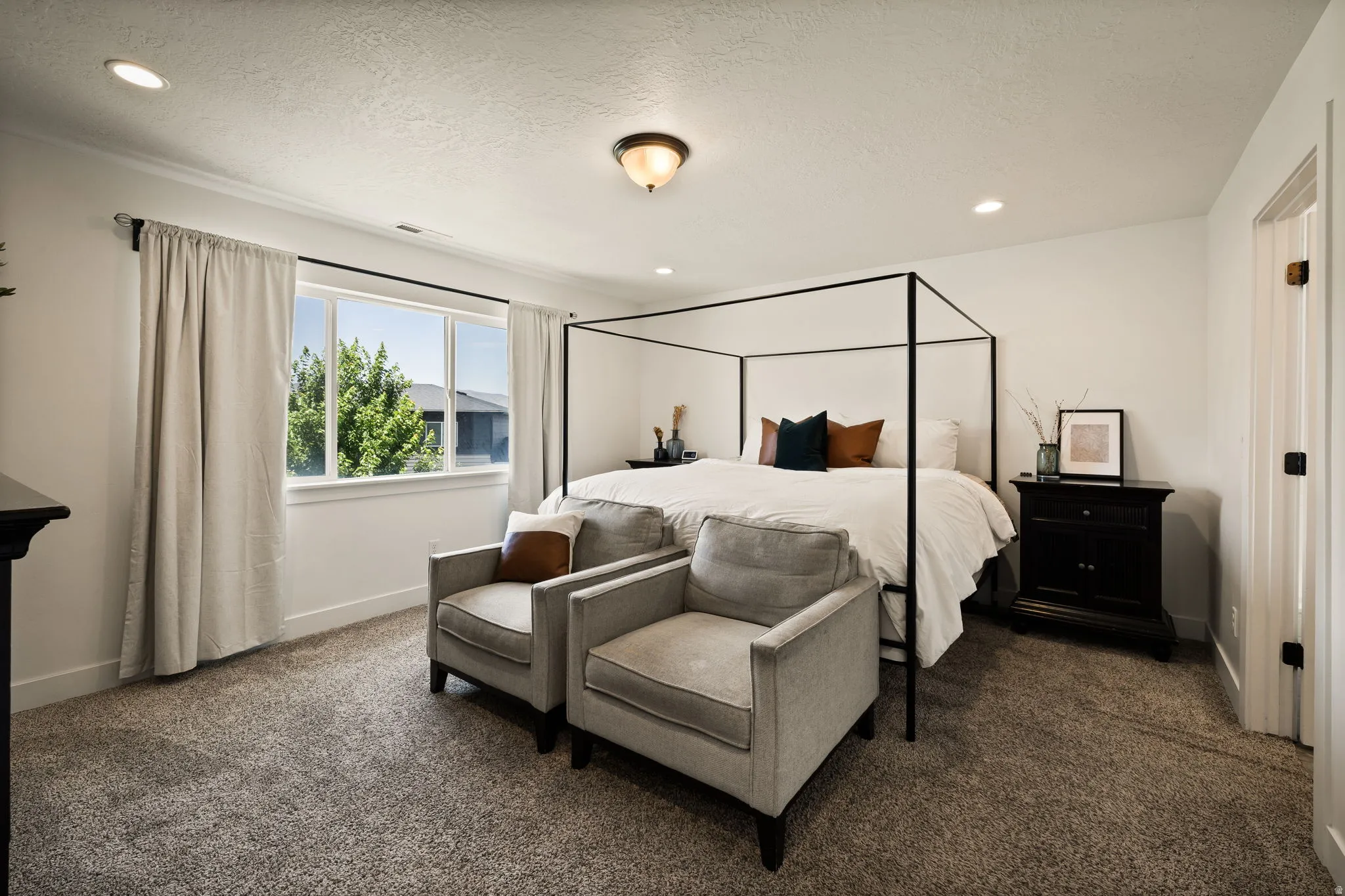 Spacious interior featuring neutral carpeting, white walls, recessed lighting, and a large window
