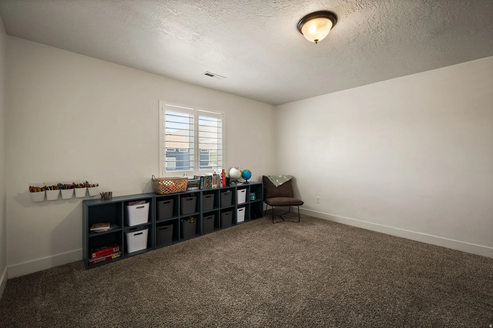 Spacious room featuring textured carpeting and white walls