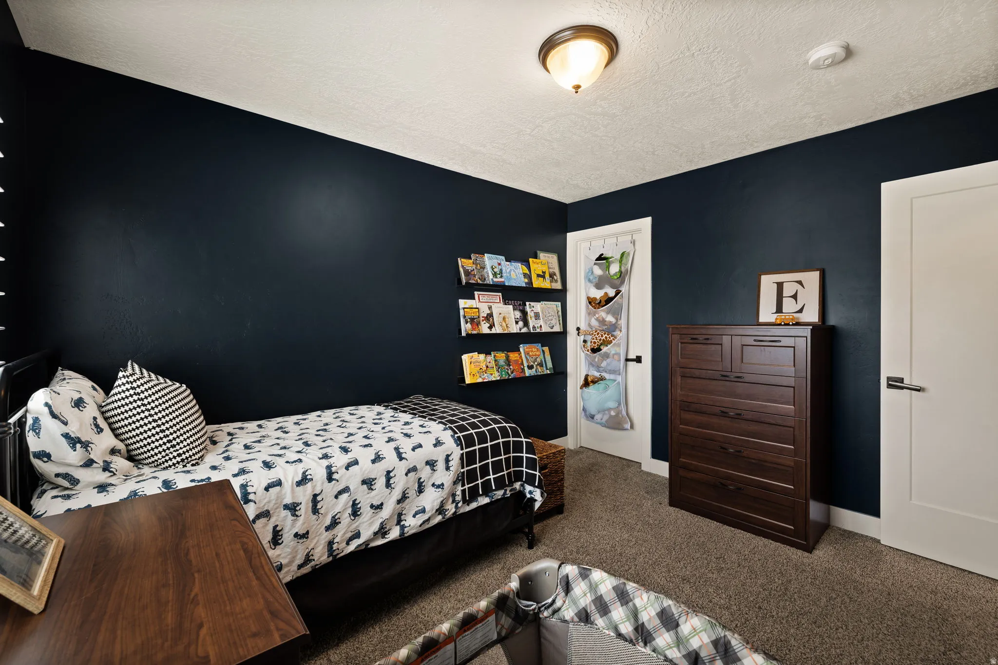 Bedroom featuring dark blue accent walls, plush carpeting, and a semi-flush mount ceiling light