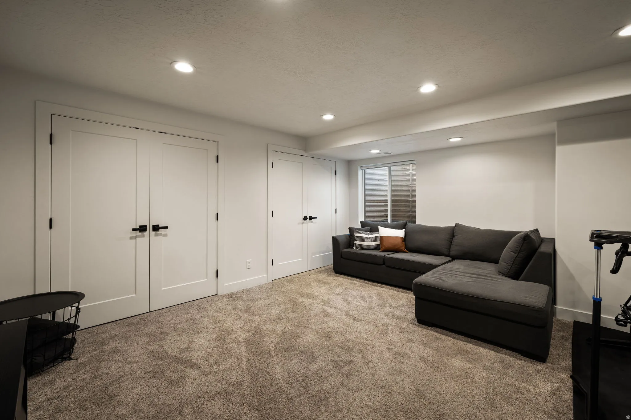 Recessed lighting illuminates this carpeted room featuring white walls and multiple white panel doors with black hardware