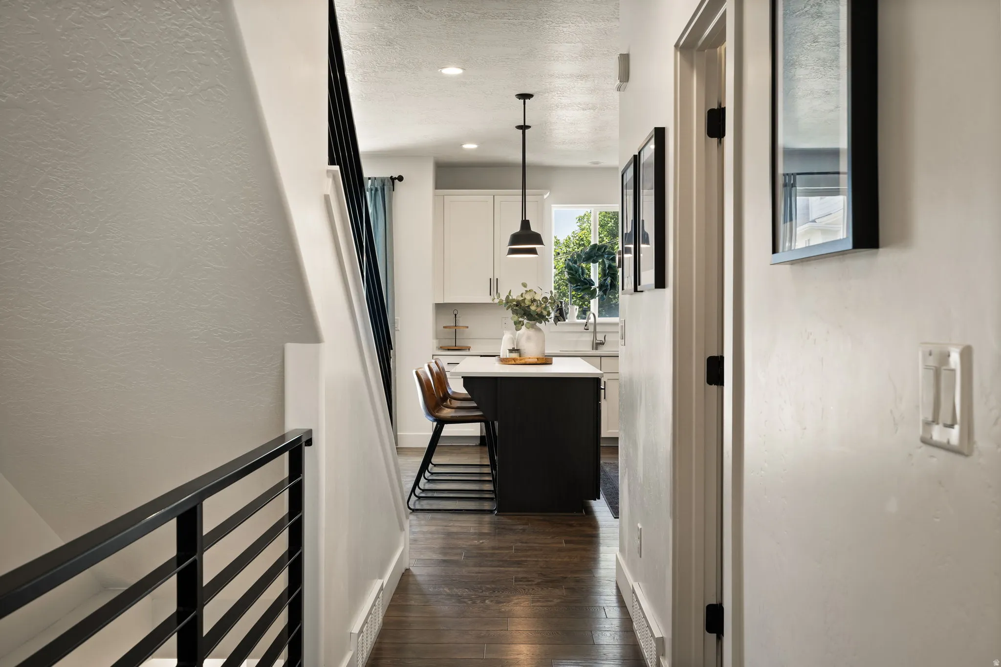 Hallway featuring dark wood-finish flooring, white walls, and a modern horizontal metal railing