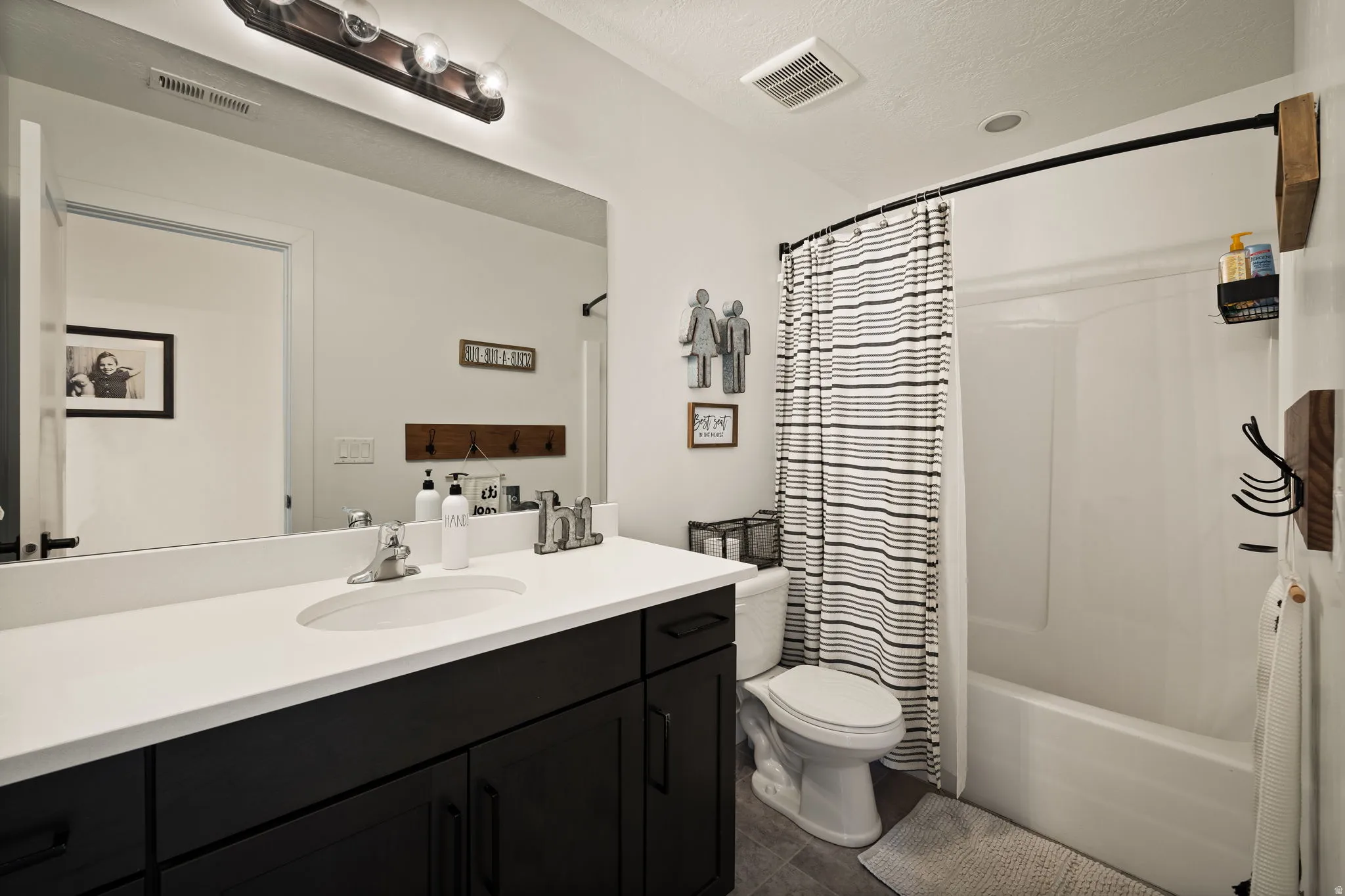 Full bathroom featuring a dark wood-finish vanity with a white countertop and integrated sink